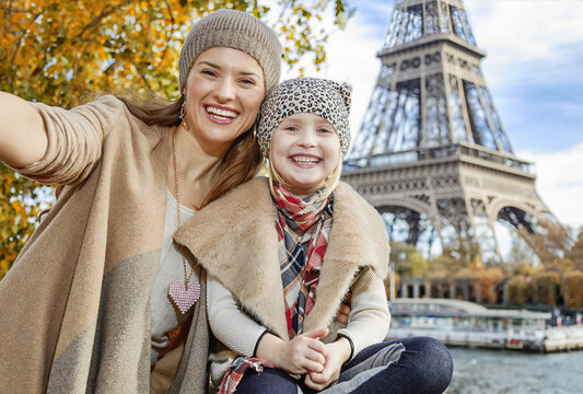 Autumn getaways in Paris with family. smiling mother and daughter tourists on embankment near Eiffel tower in Paris, France taking selfie