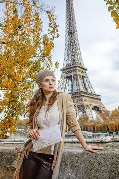 Autumn getaways in Paris. young elegant woman on embankment in Paris, France with map looking into the distance