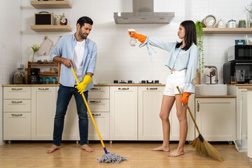 Young happy couple having fun while doing cleaning kitchen together - 622128229