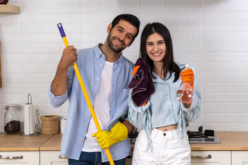 Young happy couple having fun while doing cleaning kitchen together
