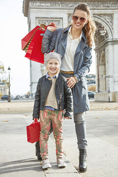 Stylish autumn in Paris. Full length portrait of smiling elegant mother and child with shopping bags in Paris, France