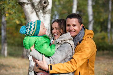 Happy family of three playing in autumn park
