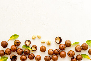 Pile of raw macadamia nuts with leaves. Healthy protein snack background