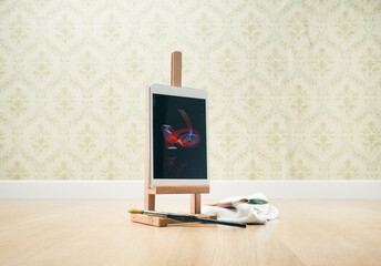 Digital tablet on wooden painting easel, vintage wallpaper on background.