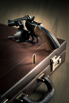 Vintage revolver with cylinder open and bullet on leather briefcase.