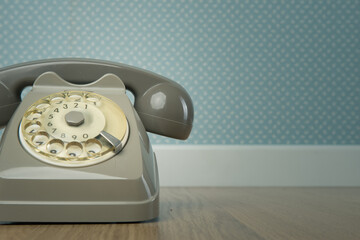 Gray vintage phone on hardwood floor and dotted light blue wallpaper on background.