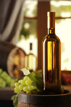 White wine bottle and grapes on wooden barrel