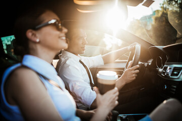 Young businessman and businesswoman driving a car and commuting to work - obrazy, fototapety, plakaty