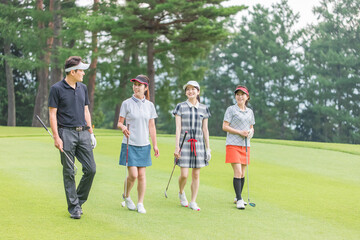 ゴルフ場を歩くゴルファーの男女（移動）
