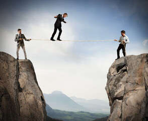 Business people holding a rope while a man balanced walking