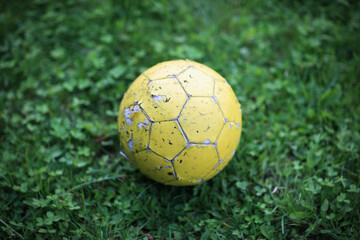 Fototapeta premium Old yellow soccer ball on green grass