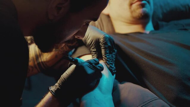 Male Artist Does Handpoke Tattoo On Man's Arm - close up