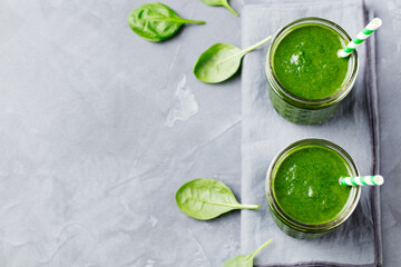 Spinach smoothie Healthy drink in glass jar on grey stone background Copy space Top view