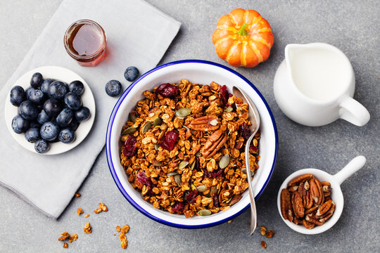 Healthy breakfast. Fresh granola, muesli with pumpkin seeds,pecan nuts and maple syrup in white bowl. Top view. Copy space