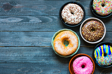 Colorful Donuts breakfast composition with different color styles of doughnuts over an aged wooden desk background.