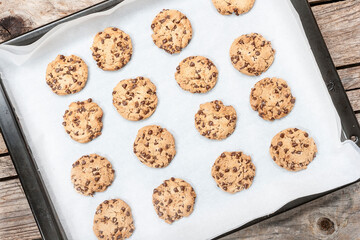 Homemade chocolate chip cookie just baked on a tray over wooden background
