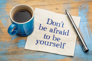 Don't be afraid to be yourself - handwriting on a napkin with a cup of espresso coffee