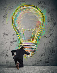 Businessman draws on the wall a big colored bulb with bright colors and business sketches