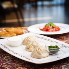 Manti, samosa and tomato salad served on plates