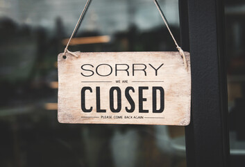 A closed sign posted on glass door of store. Concept of shop service business closed on holidays.