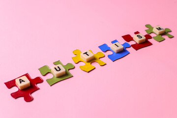 World autism awareness day concept. Autism lettering on colorful puzzles over pink background