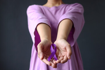 Womans hands holding purple domestic violence awareness ribbon. Alzheimer disease, Pancreatic cancer, Epilepsy awareness. Healthcare and social problem concept - Powered by Adobe