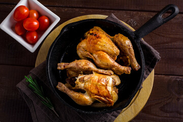 Whole roasted chicken in iron skillet on wooden board. Christmas meal
