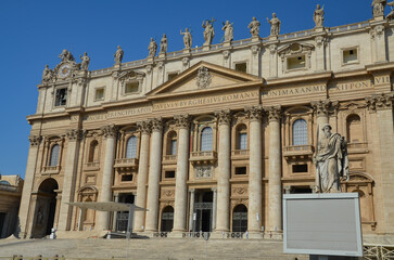 View of Saint Peter's Basilica exterior facade with sculptures, obelisk and dome.