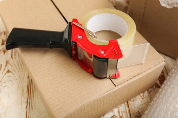 Packing tape dispenser on cardboard box, closeup