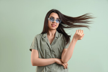 Beautiful young woman wearing stylish  sunglasses on color background