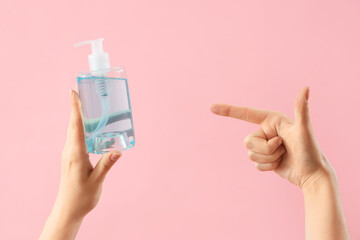 Hands with liquid soap on pink background