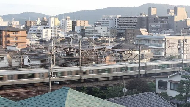 Urban train passing by in Japan in front of buildings and mountains