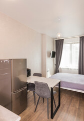 Interior design in a room with a large double bed and a table, rendering for a studio apartment