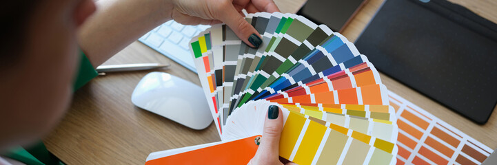 Female designer holding color samples and choosing color samples for projects.