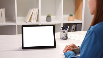 Virtual meeting. Video conference. Woman at tablet with empty space white mockup screen working on project at business call at office workplace desk.