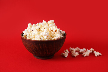 Bowl with tasty popcorn on red background