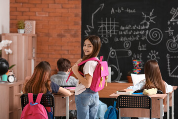 Little girl with backpack in classroom