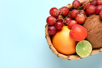 Wicker basket with different fresh fruits on blue background