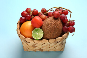 Wicker basket with different fresh fruits on blue background