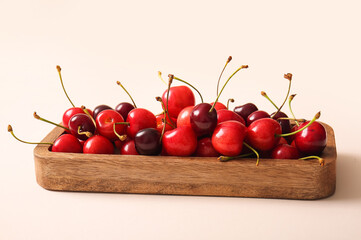 Board with sweet cherries on beige background