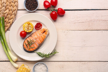 Plate with tasty grilled salmon steak on light wooden background