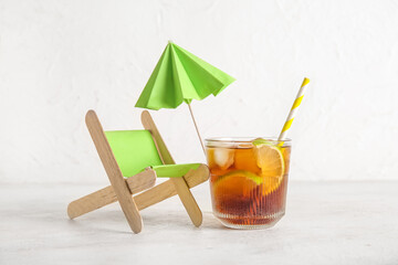 Glass of cold Cuba Libre cocktail and deckchair on white background