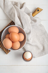 Holder with boiled chicken egg on white wooden background
