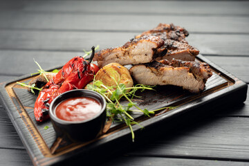Delicious barbecued ribs seasoned with grill vegetables and a spicy tomatoes sauce. Smoked American style pork ribs.