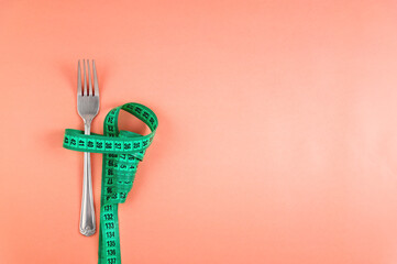 Flat style Measuring tape wrapped around a fork lying on a colored surface. Diet and weight control...