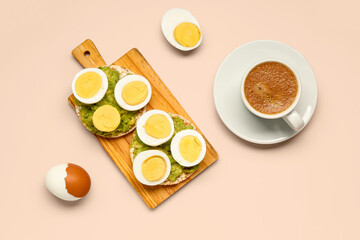 Wooden board of rice crackers with boiled eggs and avocado on pink background