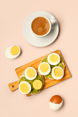 Wooden board of rice crackers with boiled eggs and avocado on pink background