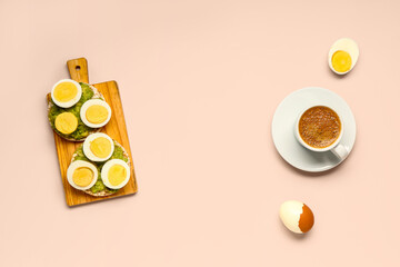 Wooden board of rice crackers with boiled eggs and avocado on pink background