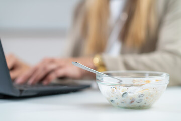 The perfect balance of work and wellness as a woman embraces healthy eating at her workplace. With a bowl of nutritious muesli and yogurt in her hand 