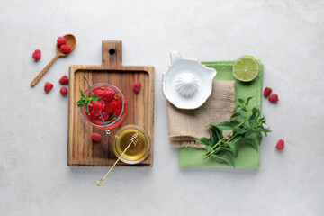 Fototapeta na wymiar Glass of fresh raspberry lemonade and bowl with honey on white background